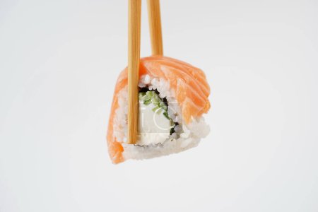Photo for Sushi roll holding in eating sticks. Japanese traditional Cuisine - Royalty Free Image