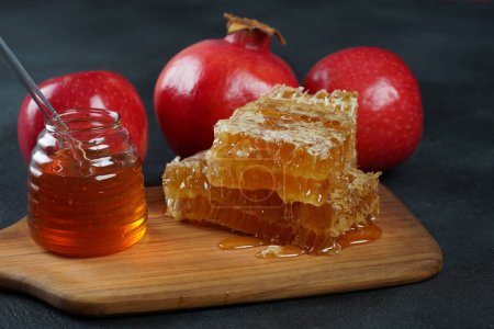 Photo for Jewish holiday Rosh Hashana celebration. Pomegranate, apples and honey traditional products for the holyday. Pouring honey on apple and pomegranate - Royalty Free Image