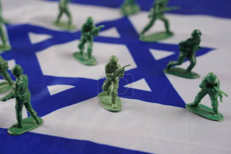 Foto de El concepto de guerra. Soldados representados por modelos de plástico verde y balas en la bandera de Israel como fondo. - Imagen libre de derechos