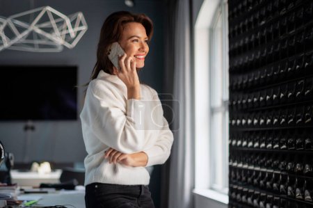Photo for Attractive businesswoman having a business call while working in a modern office. Confident female wearing business casual. - Royalty Free Image