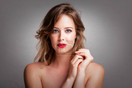 Téléchargez les photos : Headshot of gorgeous young woman with perfect skin and make-up posing at isolated grey background with copy space. Beautiful female wearing red lipstick. - en image libre de droit