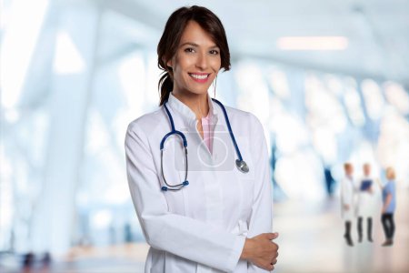 Foto de Portrait of smiling female doctor with arms crossed standing at hospital foyer. Confident healthcare worker is wearing lab coat. - Imagen libre de derechos