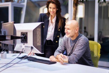 Téléchargez les photos : Les hommes d'affaires qui utilisent des ordinateurs lors d'une réunion d'affaires au travail. Femme d'affaires souriante et homme d'affaires confiant travaillant ensemble au bureau de coworking. - en image libre de droit