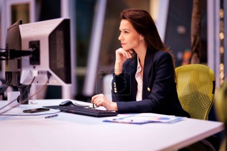 Foto de Thinkinbg mujer de negocios usando computadoras mientras está sentado en el escritorio en la oficina. Mujer profesional que trabaja en un nuevo proyecto empresarial. - Imagen libre de derechos