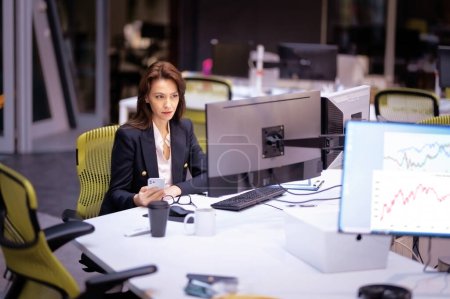 Foto de Mujer de mediana edad que usa computadoras y teléfono móvil mientras está sentada en el escritorio de la oficina. Mujer profesional que trabaja en un nuevo proyecto empresarial. - Imagen libre de derechos