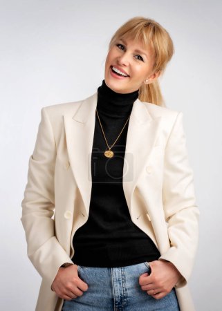 Photo for Portrait of an attractive woman smiling and looking at camera. Blond haired female wearing blazer and standing against isolated white background. Copy space. Studio shot. - Royalty Free Image