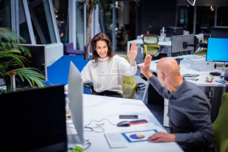 Téléchargez les photos : Heureuse femme d'affaires donnant high-five à un collègue masculin dans le bureau. Groupe de gens d'affaires travaillant ensemble dans un bureau de coworking. - en image libre de droit