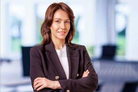 Téléchargez les photos : Jolie femme d'affaires d'âge moyen portant un blazer et debout au bureau. - en image libre de droit