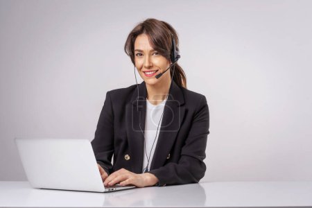 Photo for Shot of an attractive businesswoman wearing headsets while working on a computer. Isolated background. Studio shot. - Royalty Free Image