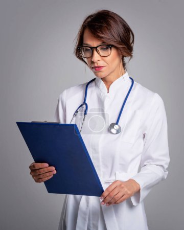 Téléchargez les photos : Pensant médecin femme tenant presse-papiers - en image libre de droit