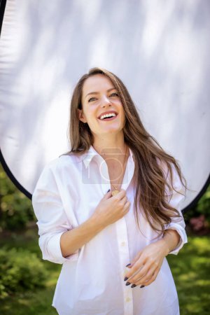 Photo for Beautiful young woman smiling against the sun. Attractive young woman having blue eyes and long brunette hair. Young female laughing - Royalty Free Image