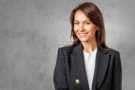 Photo for Studio portrait of attractive woman wearing white shirt and laughing while sitting at isolated dark grey background. Copy space. - Royalty Free Image