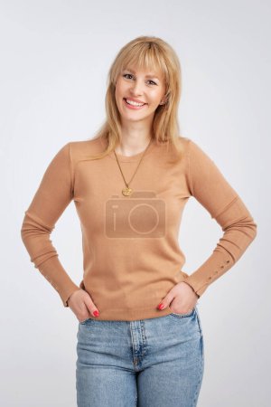Foto de Foto recortada de mujer de pelo rubio vistiendo suéter y sonriendo alegre contra bacgkround aislado. Copiar espacio. - Imagen libre de derechos