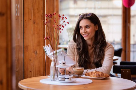 Téléchargez les photos : Belle jeune femme assise dans un café - en image libre de droit