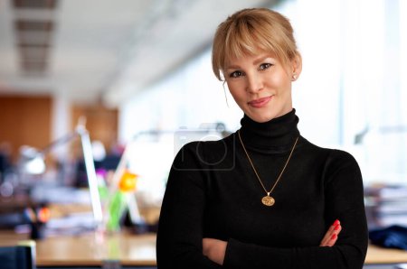 Photo for Confident businesswoman standing at the office. Blond haired professional female wearing black sweter and looking at camera. - Royalty Free Image