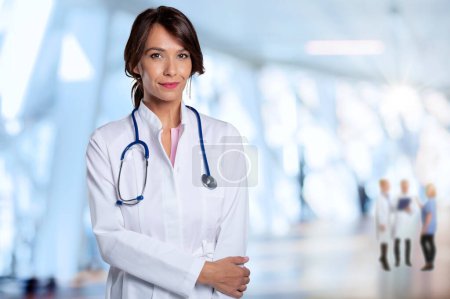 Photo for Smiling female doctor standing with arms crossed at the hospital corridor. - Royalty Free Image