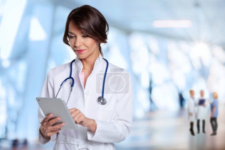 Téléchargez les photos : Portrait d'une femme médecin d'âge moyen tenant une tablette numérique debout à l'hôpital. - en image libre de droit