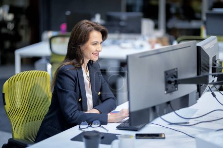 Téléchargez les photos : Femme d'affaires exécutive utilisant un ordinateur alors qu'elle était assise au bureau. Femme professionnelle travaillant sur les états financiers. - en image libre de droit