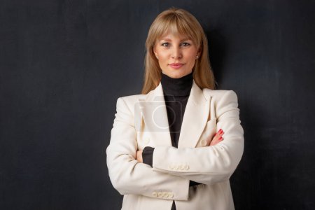 Photo for Portrait of confident mid adult businesswoman. Blond haired female is wearing business casual. She is against dark background. - Royalty Free Image
