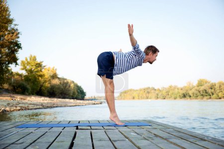Photo for Middle aged man practicing yoga outdoor. Caucasian man using yoga mat and stretching. - Royalty Free Image
