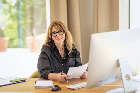 Photo for Confident businesswoman sitting at desk and using computer for work. Home office. - Royalty Free Image