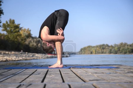 Foto de Hombre de mediana edad practicando yoga al aire libre. Caucásico hombre usando yoga mat y estiramiento en la naturaleza. - Imagen libre de derechos