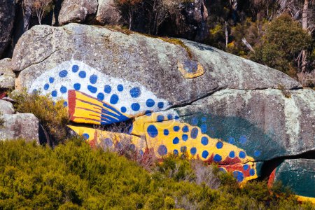 Foto de DERBY, AUSTRALIA - 23 de septiembre de 2022: Pintura aborigen de peces sobre roca y paisaje circundante en la ciudad rural de Derby en una fría mañana de primavera en Tasmania, Australia - Imagen libre de derechos