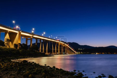 Téléchargez les photos : L'emblématique pont Tasman au crépuscule lors d'une soirée de printemps claire traversant le fleuve Derwent dans le centre de Hobart, en Tasmanie, en Australie. Tourné depuis l'estran de Clarence - en image libre de droit