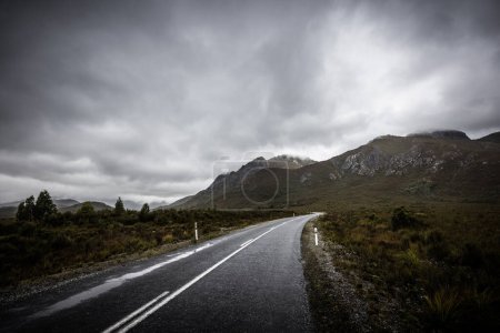 The picturesque Gordon River Rd at the Sentinel range of mountains near Bitumen Bones Sculpture on a cool wet summers morning in Southwest National Park, Tasmania, Australia