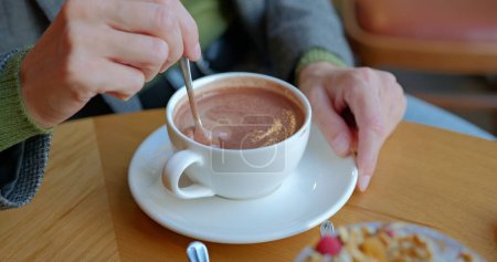 Photo for Girl hand stirs hot chocolate in white cup with spoon. Woman with creamy chocolate in cafe. High quality photo - Royalty Free Image