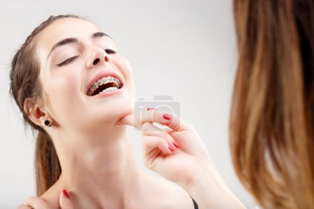 Nahaufnahme des Mädchengesichts, lächelnd, um Zahnspangen dem Zahnarzt zu zeigen. Experte untersucht Kieferorthopädie und Mundgesundheit und erfreut den jungen Patienten
