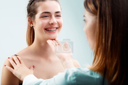 Chica sonriente en primer plano muestra frenos al dentista. Comprobación experta de la salud bucal y ortodoncia, satisfaciendo profesionalmente al paciente