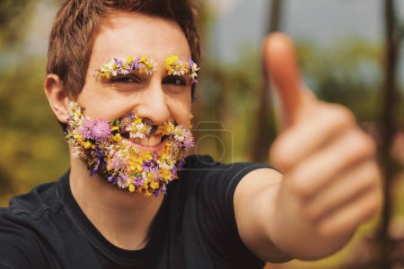 Colorful blossoms transform a man's usual facial hair. Exuberantly, he gestures thumbs-up, believing in the energies of Earth and asking for your trust