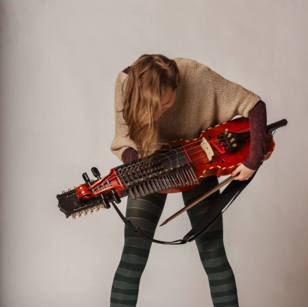 musician closely inspects her nyckelharpa, a rare traditional Swedish instrument, ensuring every detail is perfect