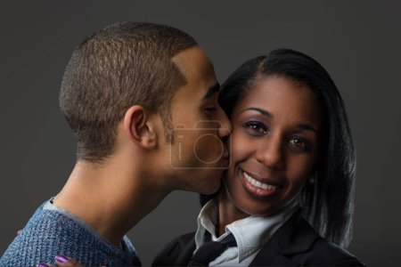 young man kisses a woman's cheek; her expression is a complex tapestry of appreciation tinged with concern
