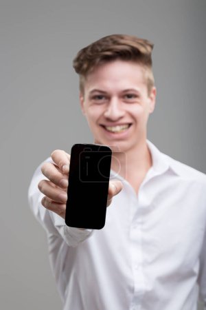 Engaged young man showcases his smartphone, pairing technology with a sharp sense of attire