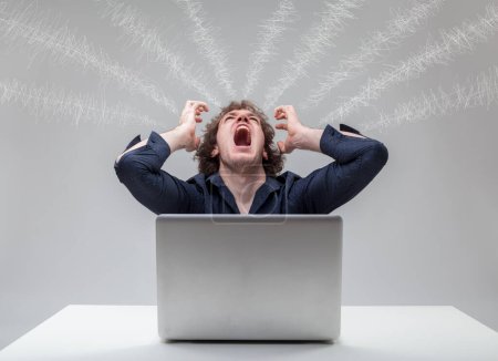 Frustrated male pulls hair in front of computer, shockwaves above indicate intense psychological strain