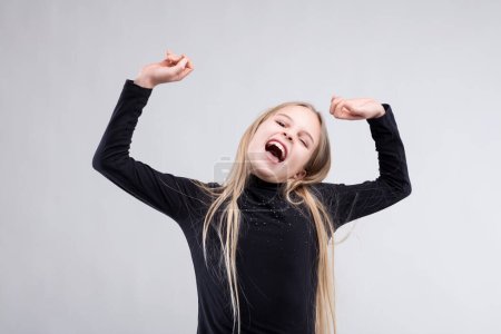 Exuberant young girl with arms raised celebrates joyfully, her laughter echoing the essence of loudness
