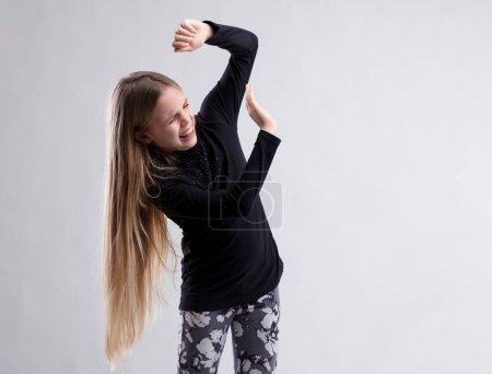 Young girl defensively raises her arms, grimacing as if to ward off something repulsive or frightening