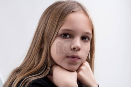 Portrait of a pensive young girl, hands resting on her chin, exuding a serene calmness