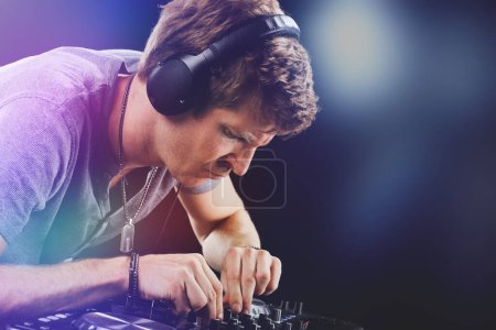 Das Engagement eines DJs bei der Arbeit wird festgehalten, während er die Mischpultsteuerung akribisch einstellt