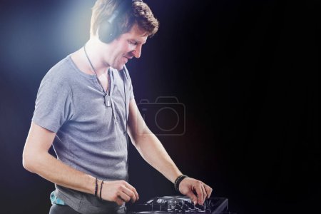 DJ profondément absorbé dans son mix, avec casque allumé, se concentre intensément sur la table d'harmonie