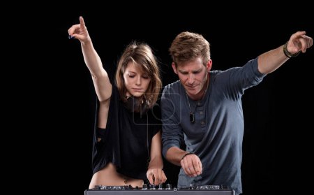 male and female DJ share a lighthearted moment, smiling over the music mixer in camaraderie