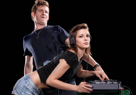 El DJ masculino hace guardia mientras la hembra se concentra en la mezcla, un estudio en equipo