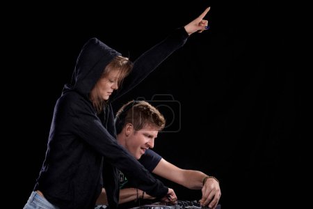 DJ partners synchronize, pointing decisively, indicating a shared understanding of the music's flow