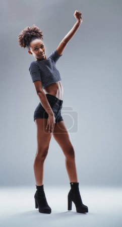 Woman poses with fist raised, empowerment radiating from her confident stance and stylish outfit