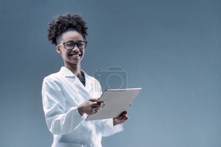 Smiling tech specialist in white coat, tablet in hand, epitomizes cutting-edge AI research and application