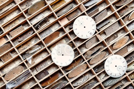 Precisely arranged watch faces in wooden grids stand ready for their mechanical symphony to resume