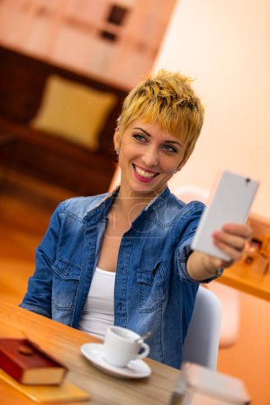 She finds joy in a simple caf moment, her smile infectious as she takes a playful selfie 