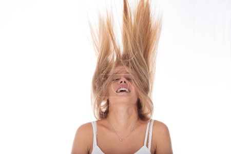 Full of life, young woman with hair tossed high laughs against a bright background